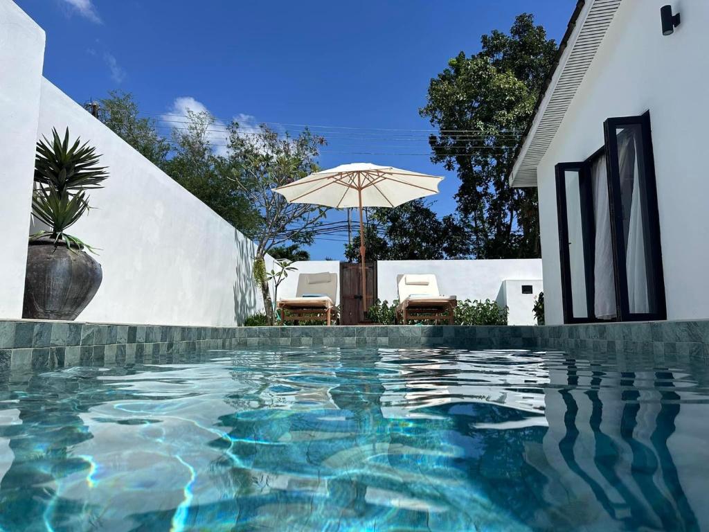 een zwembad met een parasol naast een huis bij Arau House in Arau