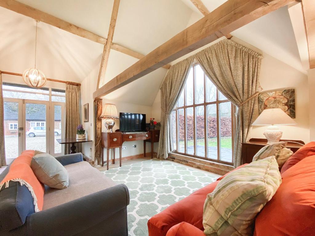 a living room with a couch and some windows at Bushton Barn in Royal Wootton Bassett