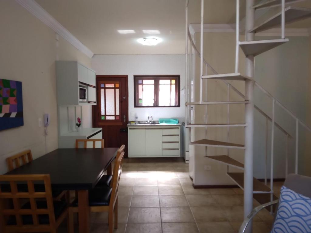 a kitchen and dining room with a table and a staircase at Apartamento Duplex a 100 metros da Praia de Boracéia in Bertioga