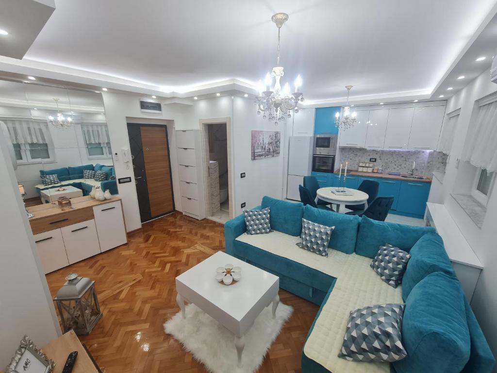 a living room with a blue couch and a kitchen at Apartman Milos free parking in Kraljevo