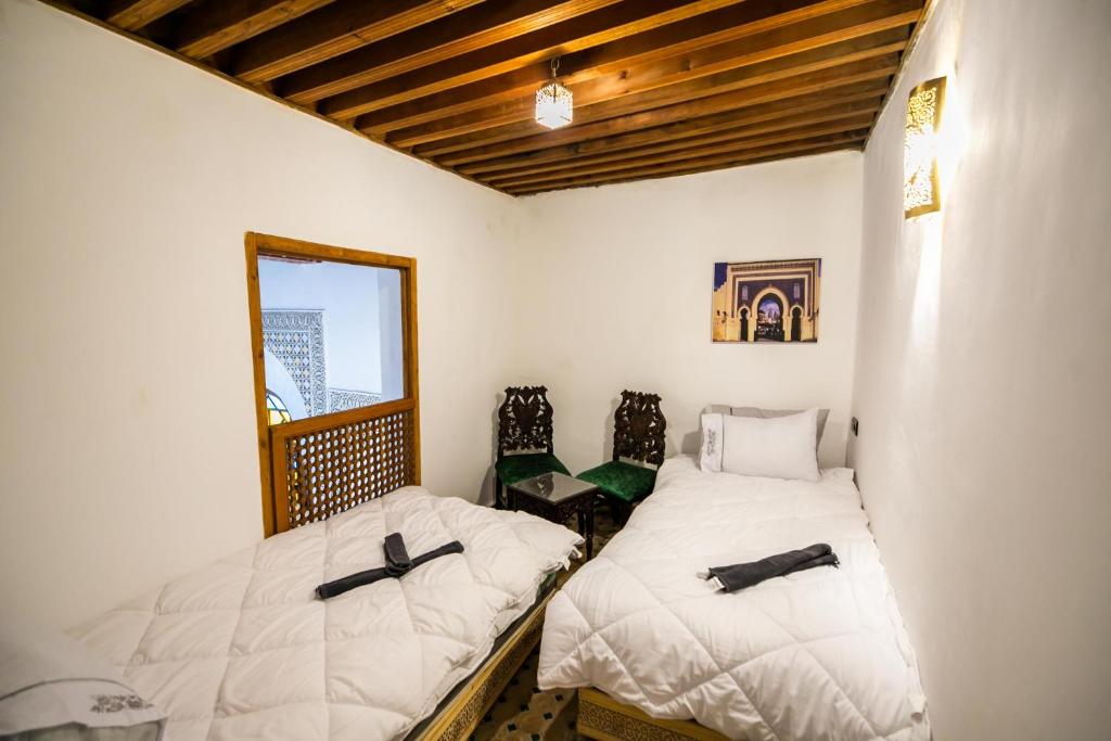 a bedroom with two beds and a mirror at Palais Chahd Luxury in Fez