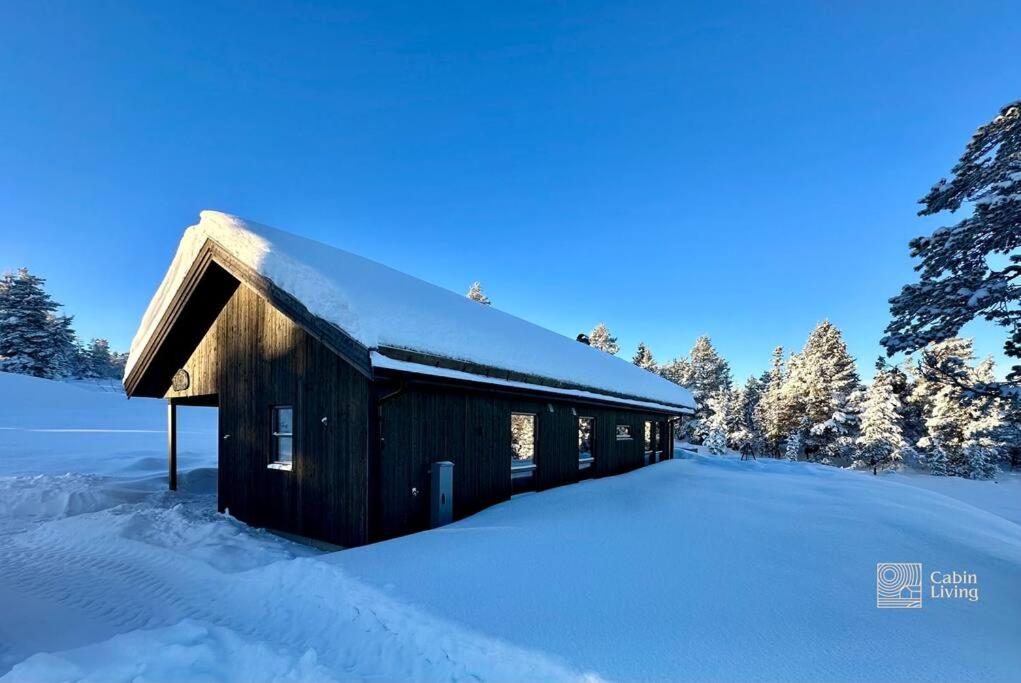 un granero de madera cubierto de nieve en un campo en New cabin near X Country ski trails at Blefjell with Jacuzzi, en Flesberg