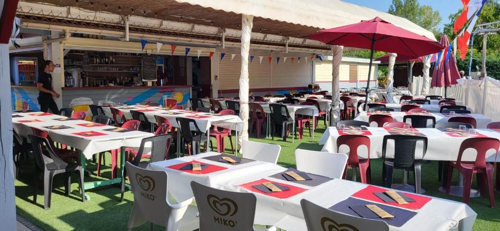 a group of tables and chairs with umbrellas on the grass at Camping Les Lacs de Courtès in Estang