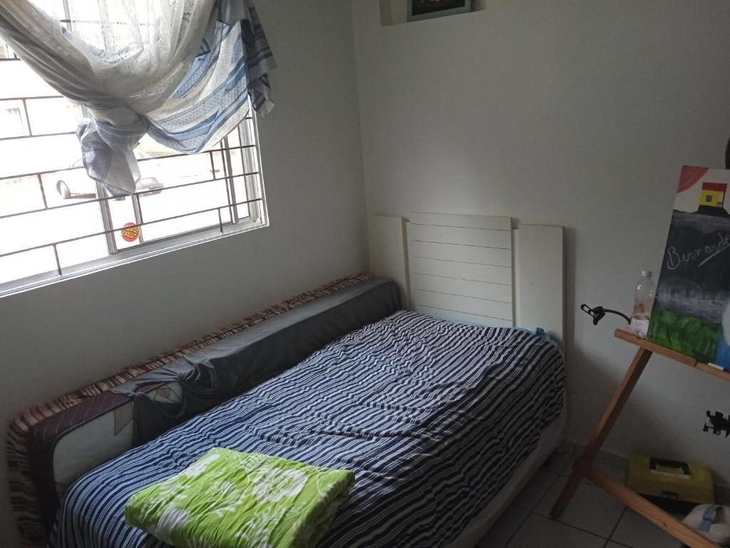 Habitación pequeña con cama y ventana en Apto 2px.unesc, en Criciúma