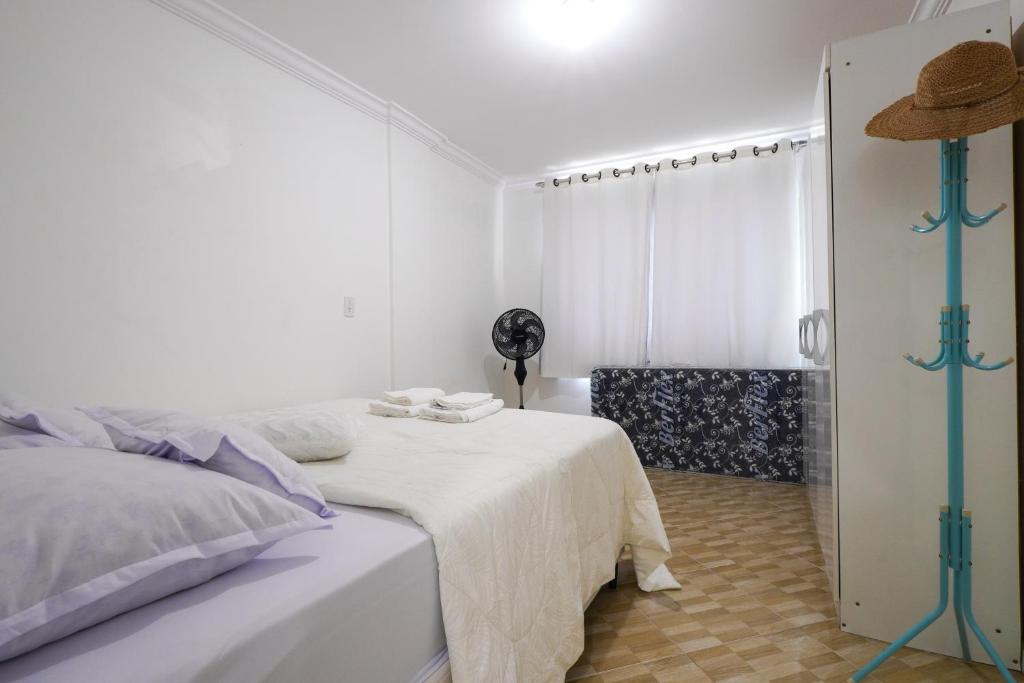 a white bedroom with a bed and a window at Apartamento na praia - Canto da Sereia in Piçarras