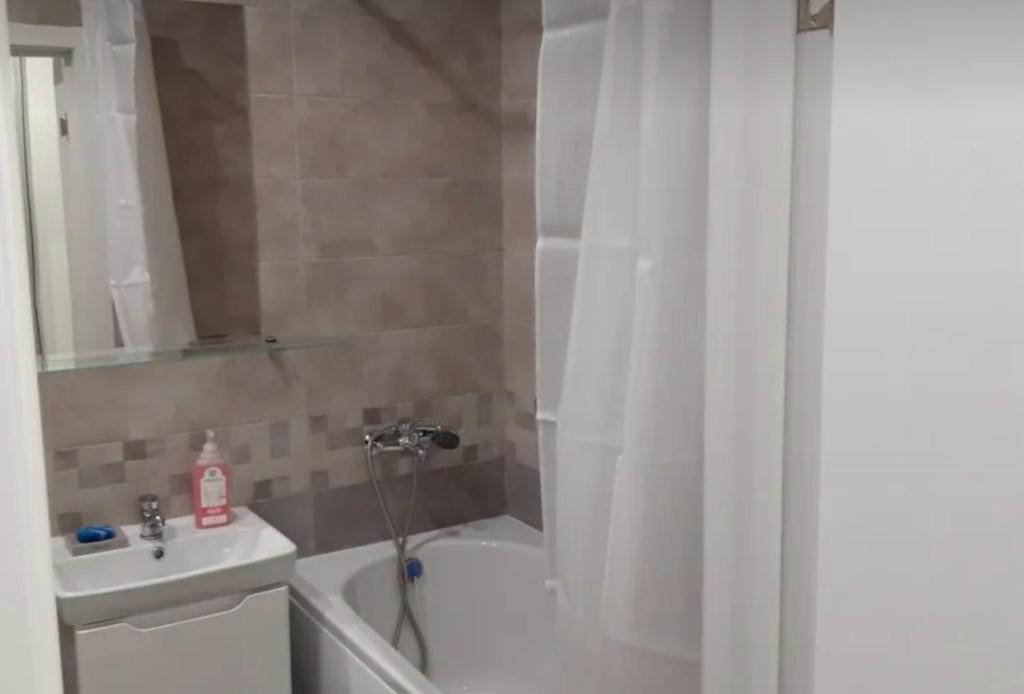 a bathroom with a white shower curtain and a sink at VIP apart 748 in Tbilisi City
