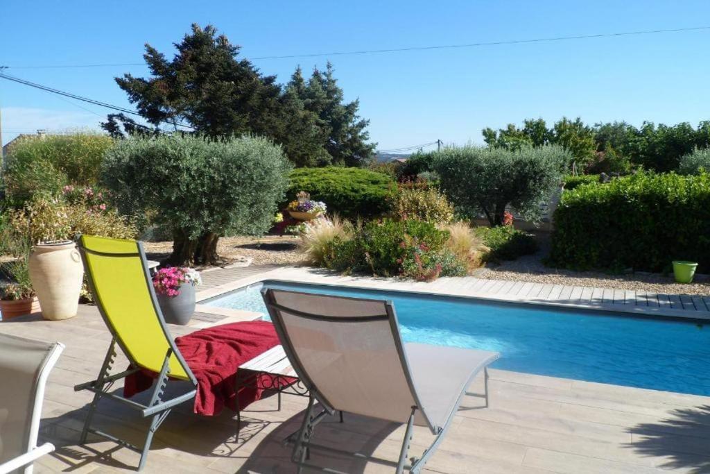 twee stoelen en een tafel naast een zwembad bij Maison avec piscine in Villeneuve