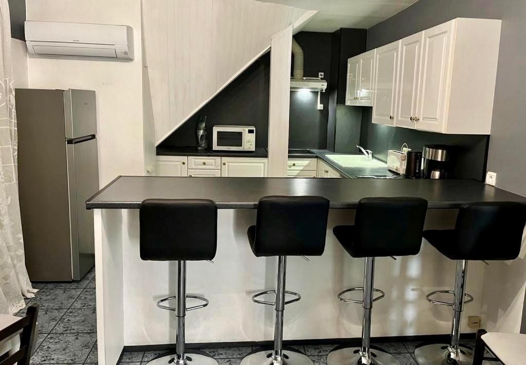 a kitchen with a counter with four bar stools at Cosy apartment proche Paris et Disneyland in Gagny