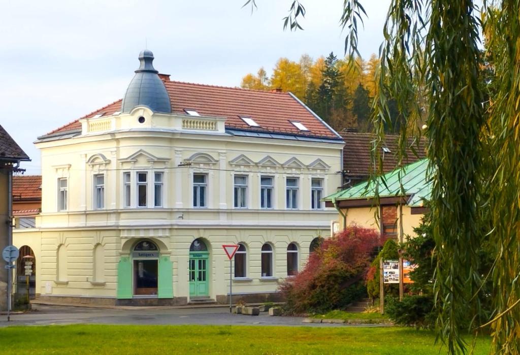 un grand bâtiment blanc avec un toit rouge dans l'établissement Vila Antik, à Nové Hrady