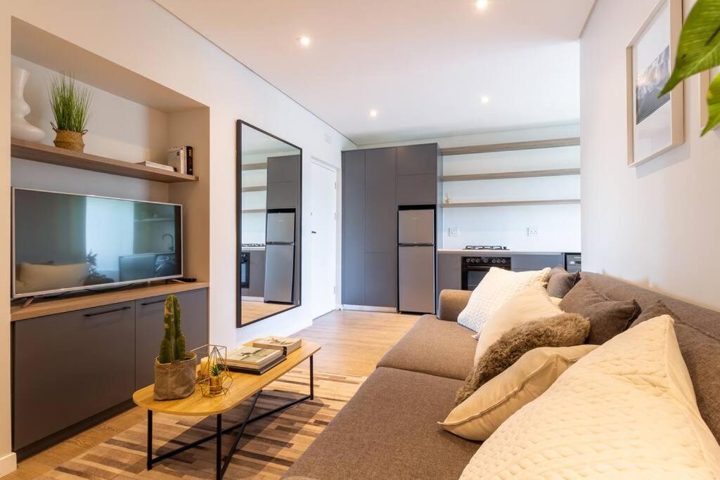 een woonkamer met een bank en een tv bij Contemporary central apt. Between beach and city. in Kaapstad