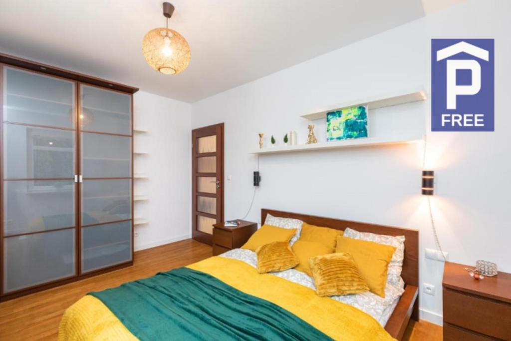 - une chambre dotée d'un lit avec des oreillers jaunes et verts dans l'établissement SuperApart Wilanowska 7, à Varsovie