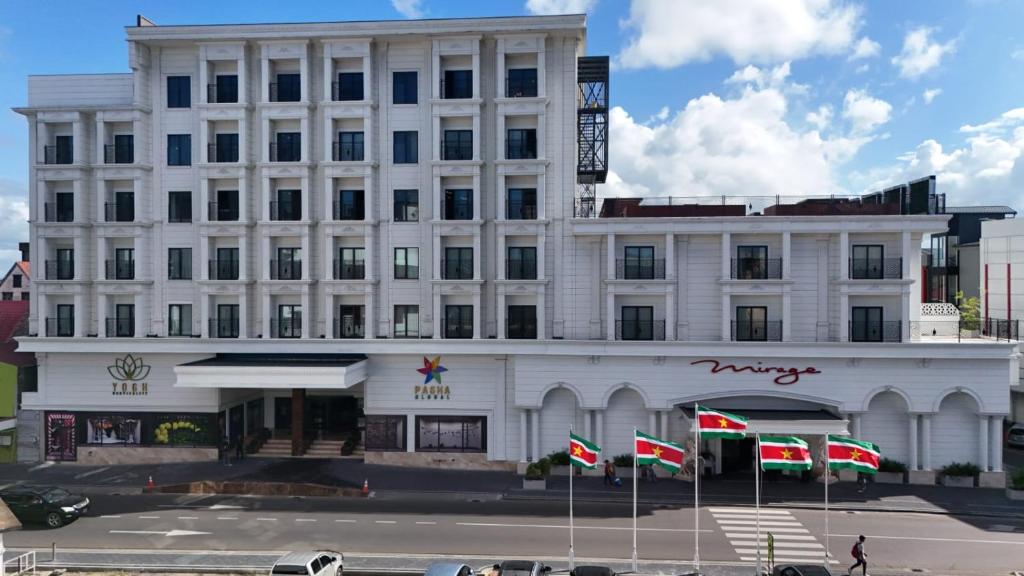 een wit gebouw met vlaggen ervoor bij Yogh Hospitality in Paramaribo