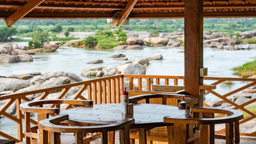 una mesa y sillas en una terraza con un río en Leo Woods Hampi River view, en Hampi