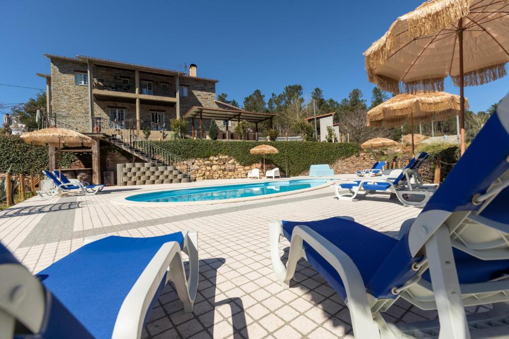 a pool with blue and white chairs and a building at Quinta do Rio Alva and Glamping Lodges in Mouronho