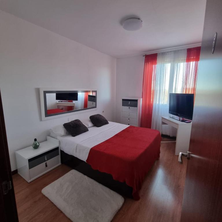 een slaapkamer met een bed met een rode deken en een televisie bij Habitación confort 