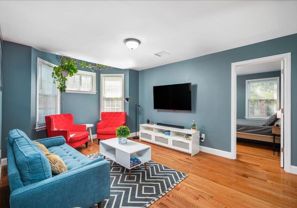 Colorful, Comfy & Modern - Close to NYC - Parking! في Mount Vernon: غرفة معيشة بجدران زرقاء وكراسي حمراء
