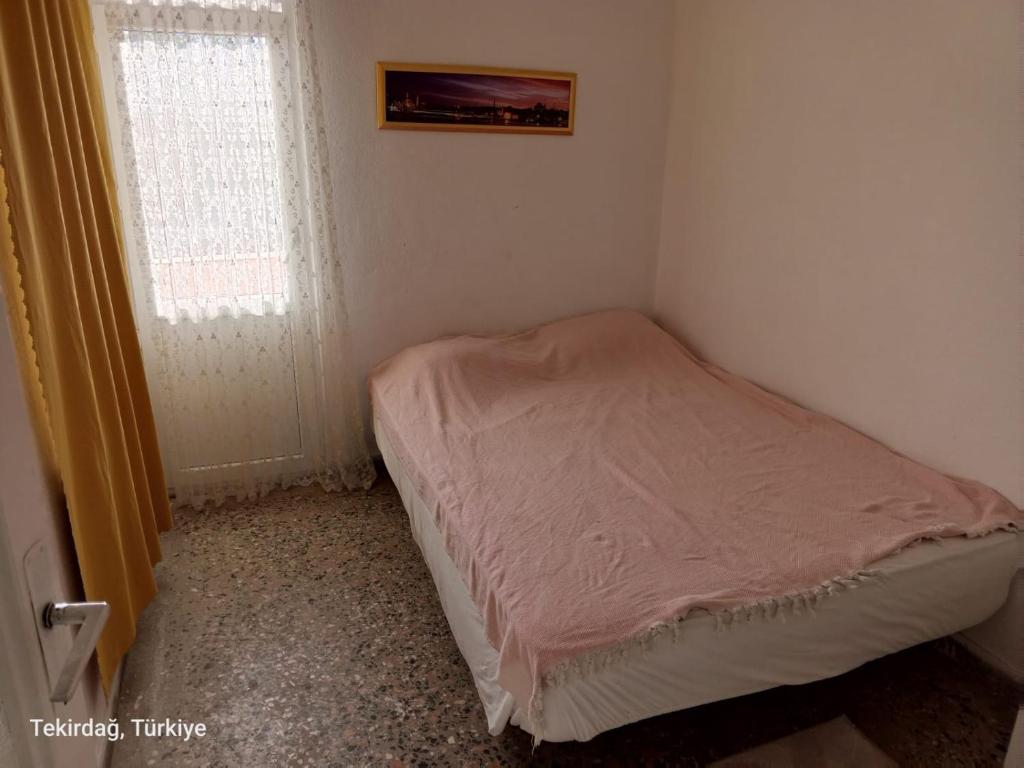 małe łóżko w małym pokoju z oknem w obiekcie Deniz Yıldızı Apart w mieście Marmaraereglisi