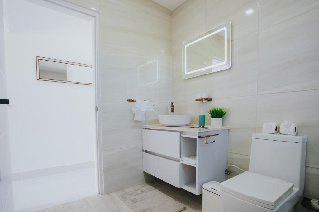 a white bathroom with a toilet and a sink at Hidden Villa Aruba in Oranjestad