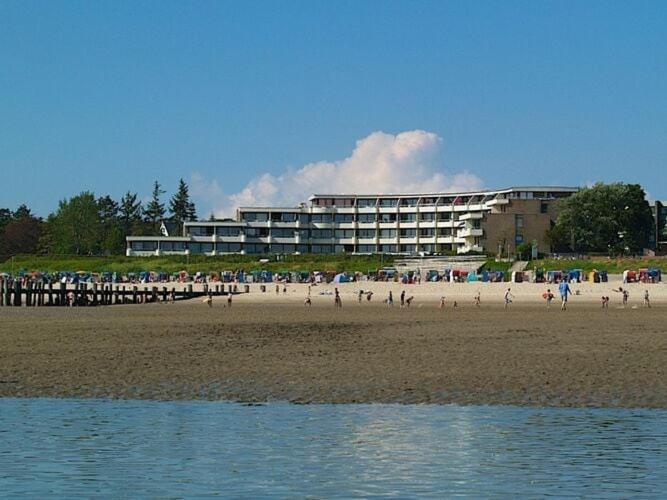 un groupe de personnes sur une plage près d'un hôtel dans l'établissement Holiday apartment with sea views of Föhr, à Wyk auf Föhr