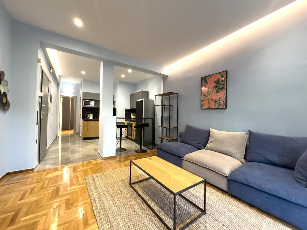 sala de estar con sofá azul y mesa en Osiris Hideaway Inn, Kerameikos, Athens, Industrial 2-br apt, balconies & Netflix, en Atenas