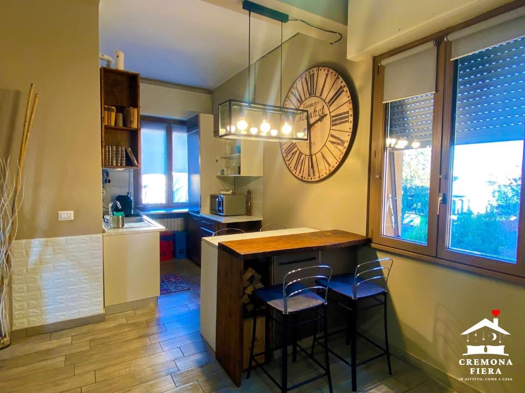 a kitchen with a bar with stools and a clock on the wall at APPARTAMENTO CREMONA FIERA in Cremona