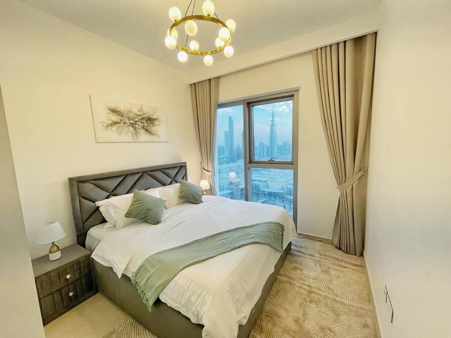 a bedroom with a bed with a chandelier and a window at Downtown, Burj Khalifa Views, Dubai Mall Connected in Dubai