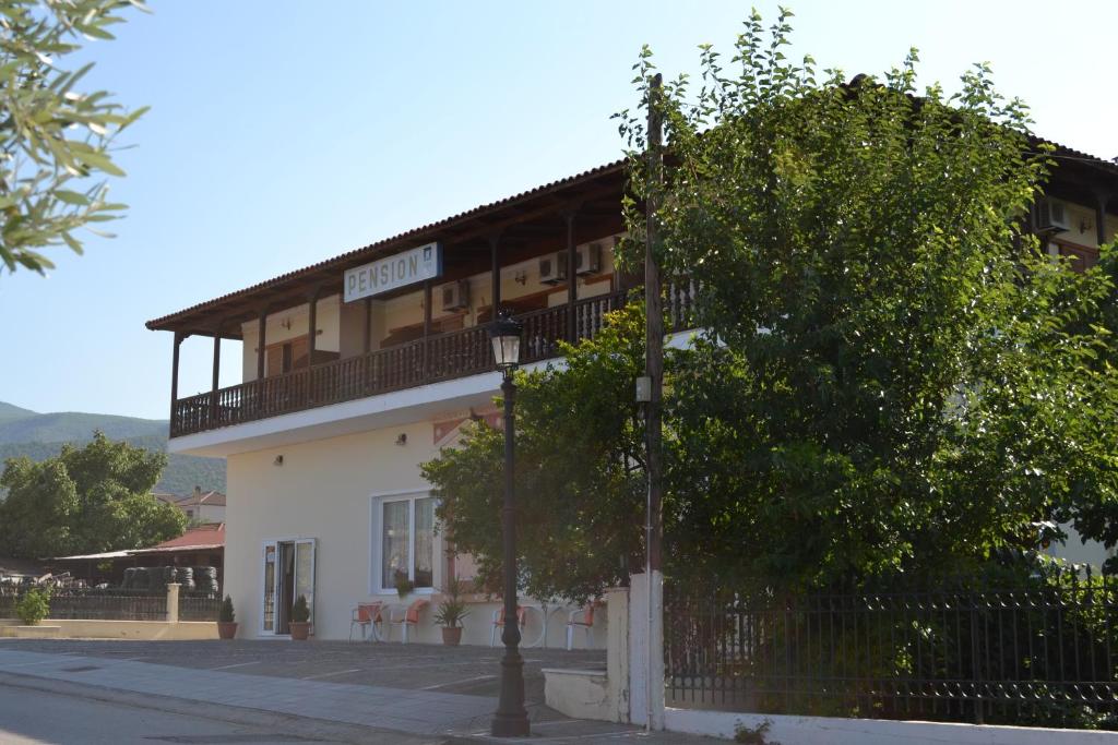 un bâtiment sur le côté d'une rue avec un arbre dans l'établissement Pension Vergina, à Vergina