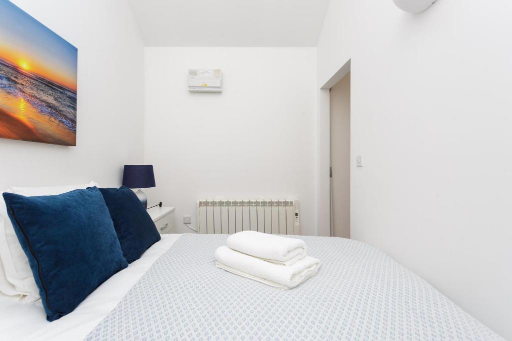 a bedroom with a white bed with blue pillows at Stylish Self-Contained Annex near City Centre in Southampton