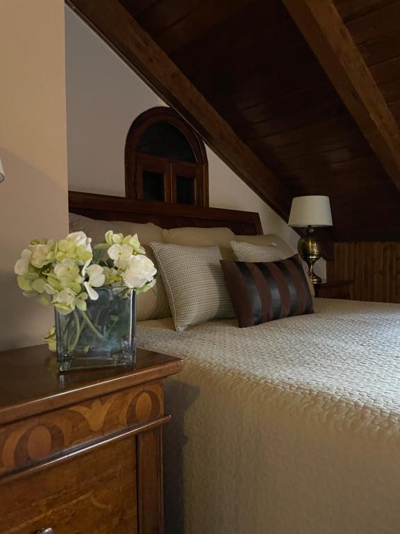 a bedroom with a bed with a vase of flowers on a table at Porfyra Luxury Guesthouse in Kalavrita