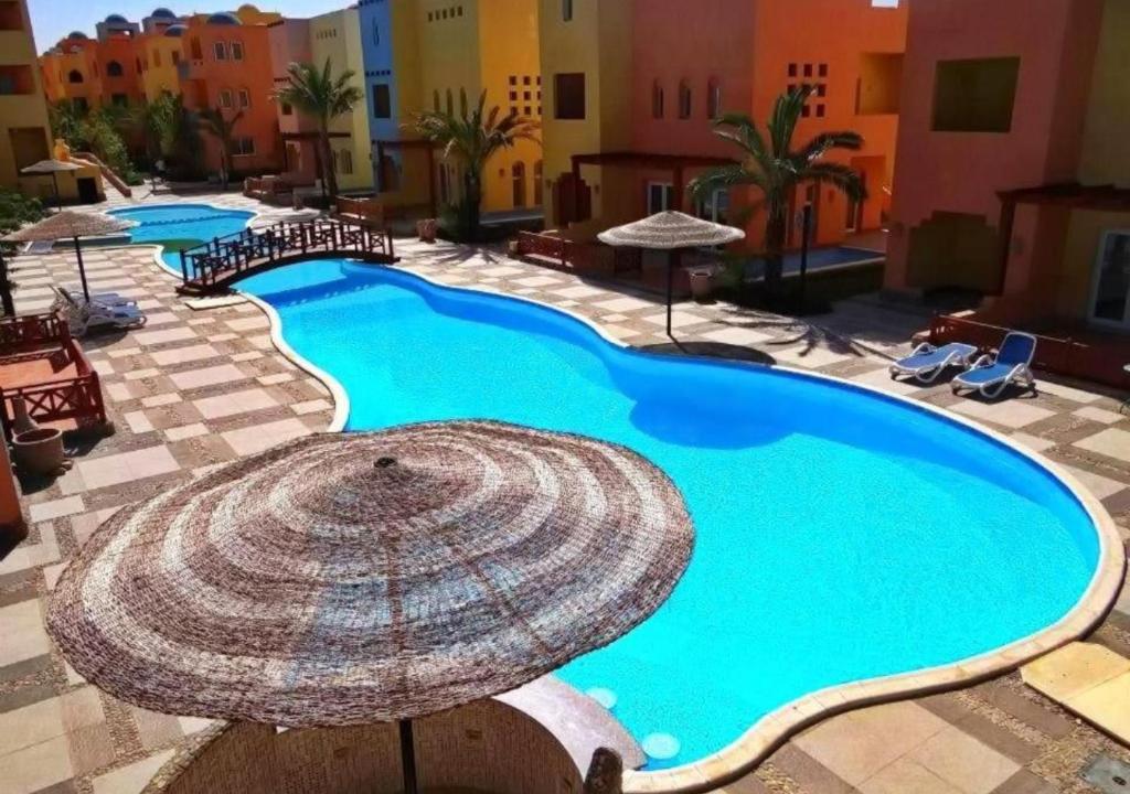 a large swimming pool with a umbrella on a resort at Al Dora Residence Suites Hurghada in Hurghada