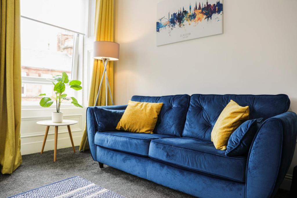 ein blaues Sofa mit gelben Kissen im Wohnzimmer in der Unterkunft Glasgow, Bothwell, 3 bed, Suitable for Long Stays in Bothwell