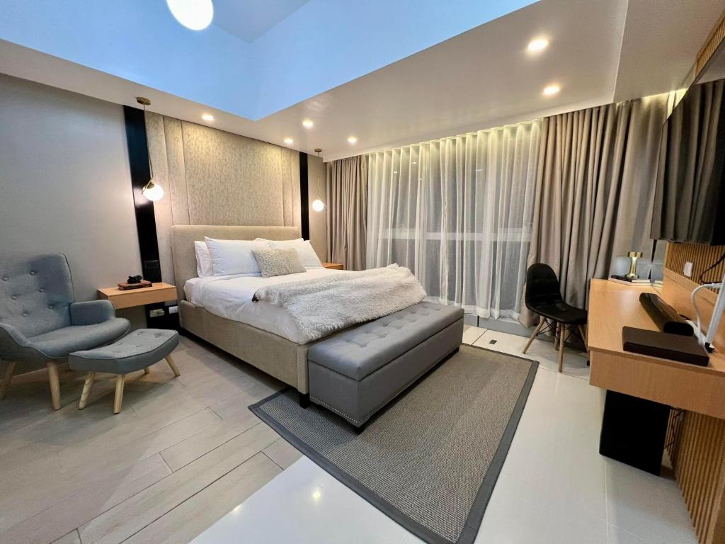 a bedroom with a bed and a desk and a chair at Hotel Vibe Condo at Uptown Parksuites BGC in Manila