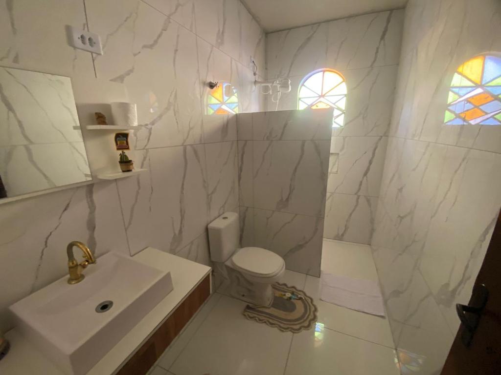 a white bathroom with a sink and a toilet at Quarto privativo no centro de Foz in Foz do Iguaçu