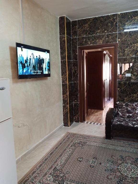a room with a television on a wall with a couch at شقة ام نوارة الحديثة in Amman