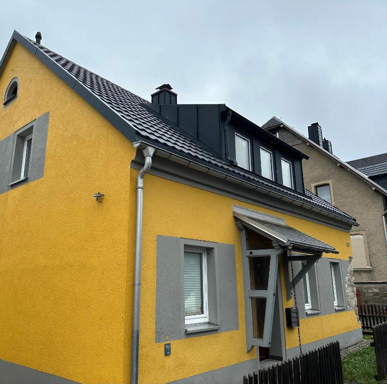een geel huis met een zwart dak bij Berghaisl Neudorf in Neudorf