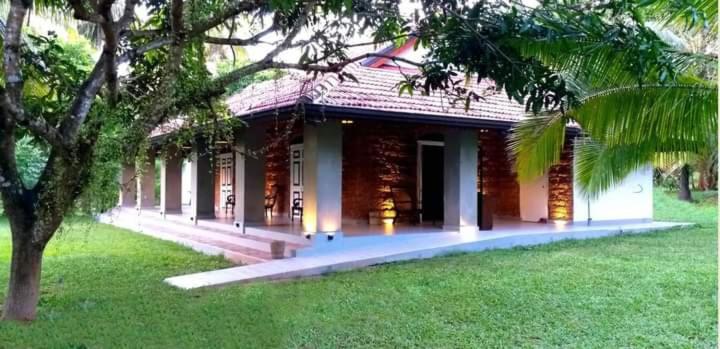 a building with a green yard with a tree at Coco Villa Cinnamon in Negombo