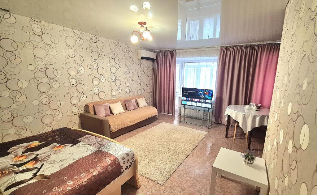 a bedroom with a bed and a couch and a tv at 1 комнатная квартира в центре in Uralsk