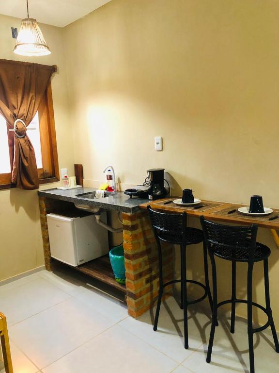 a kitchen with a counter with stools in a room at Suite Compacta Wind Jeri in Jericoacoara