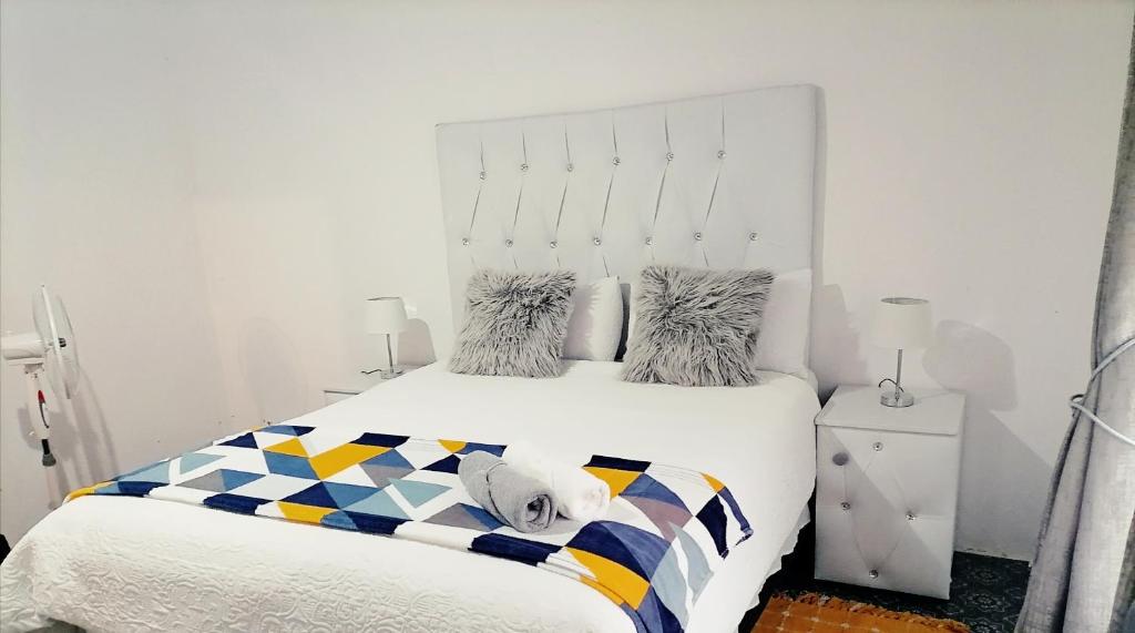 Dormitorio blanco con cama blanca y manta colorida en Drakensview guesthouse en Acornhoek