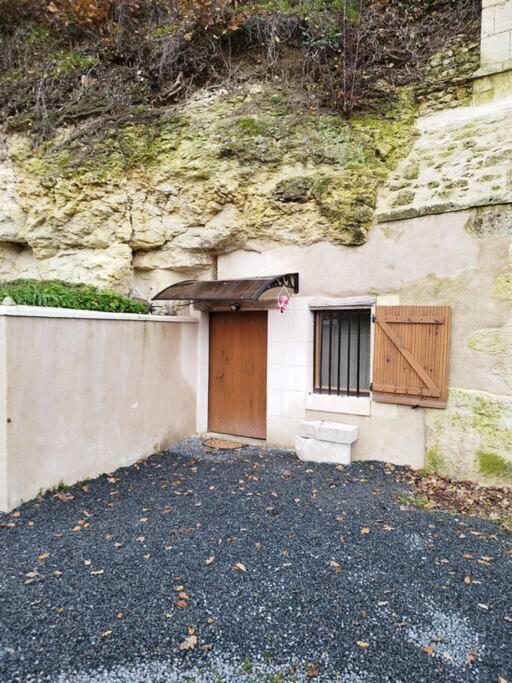 un edificio con puerta de madera y pared de piedra en Petite maison troglodyte en Le Grand-Pressigny