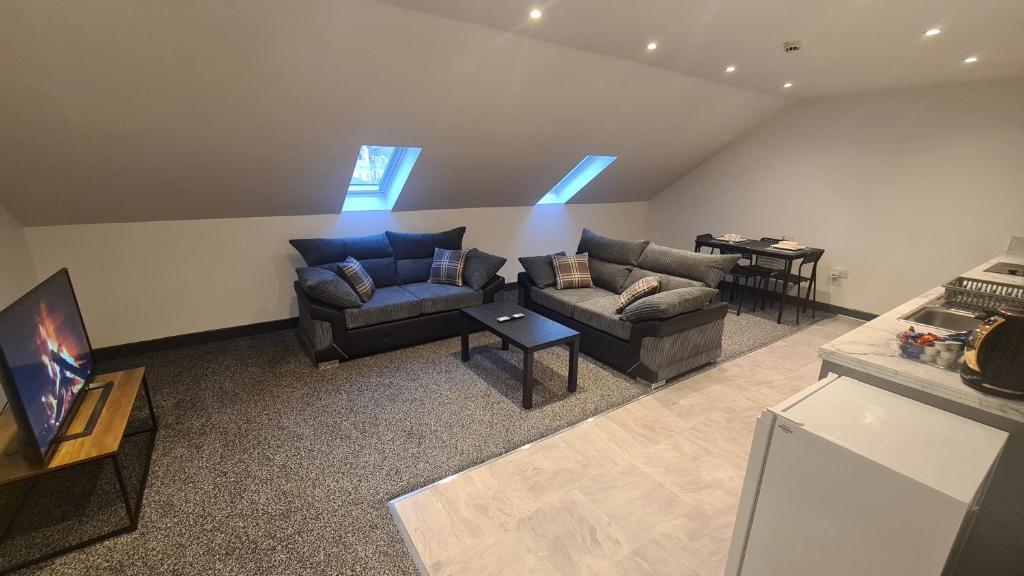 ein Wohnzimmer mit 2 Sofas und einem TV in der Unterkunft Homestay by BIC Oates 9 in Dewsbury