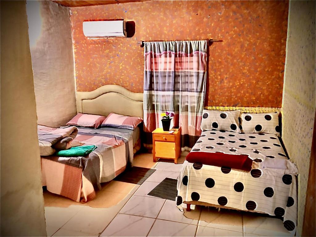 1 Schlafzimmer mit 2 Einzelbetten und einem Fenster in der Unterkunft La escala aeropuerto in Luque