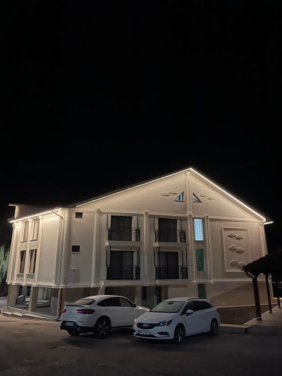 two cars parked in front of a building at night at Conacul Peștera Urșilor in Chişcău