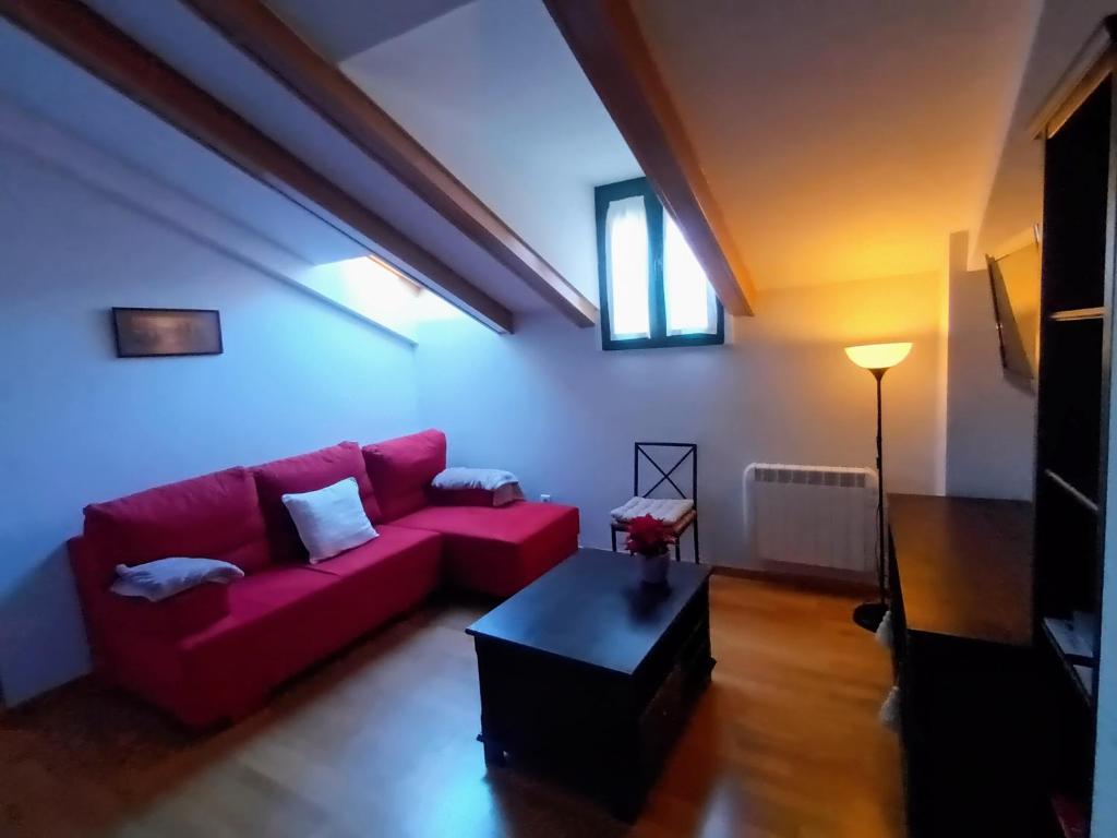 a living room with a red couch and a table at Arrabal de Santa María in Sigüenza