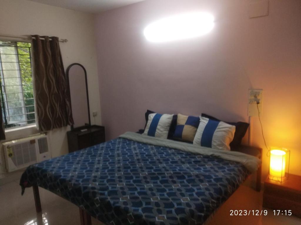 um quarto com uma cama com um edredão azul e uma luz em Royale Seaward Cozy Suite em Chennai
