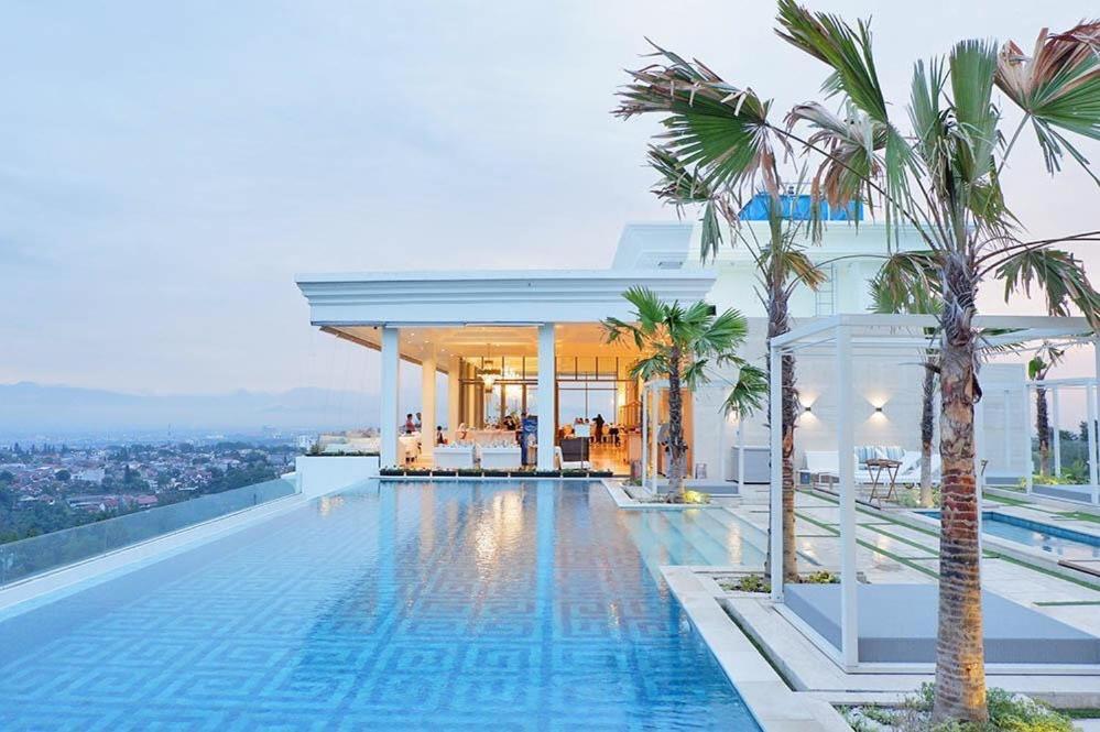 Deluxe Room @ ArtDeco Luxury Hotel & Residence By Parker House في باندونغ: مسبح على سطح منزل به نخيل