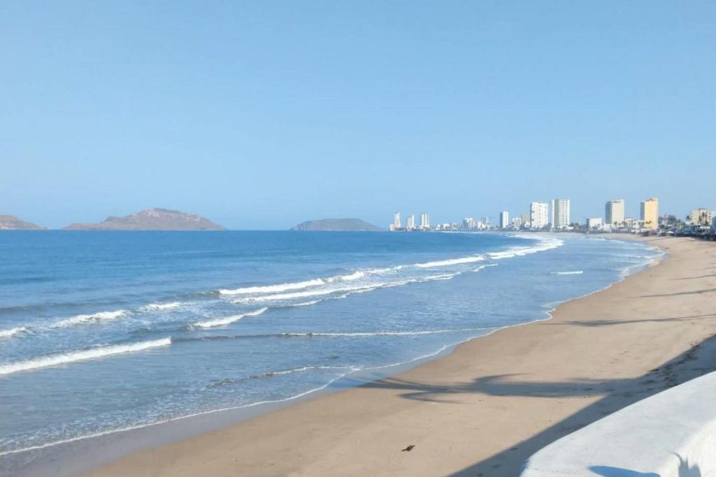 a view of the beach with buildings in the background at Descanso Esencial Azul - 7 Min Malecón y Playas in Mazatlán