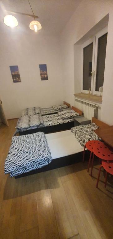 three beds in a room with a table and chairs at Kwatery pracownicze in Tomaszów Mazowiecki