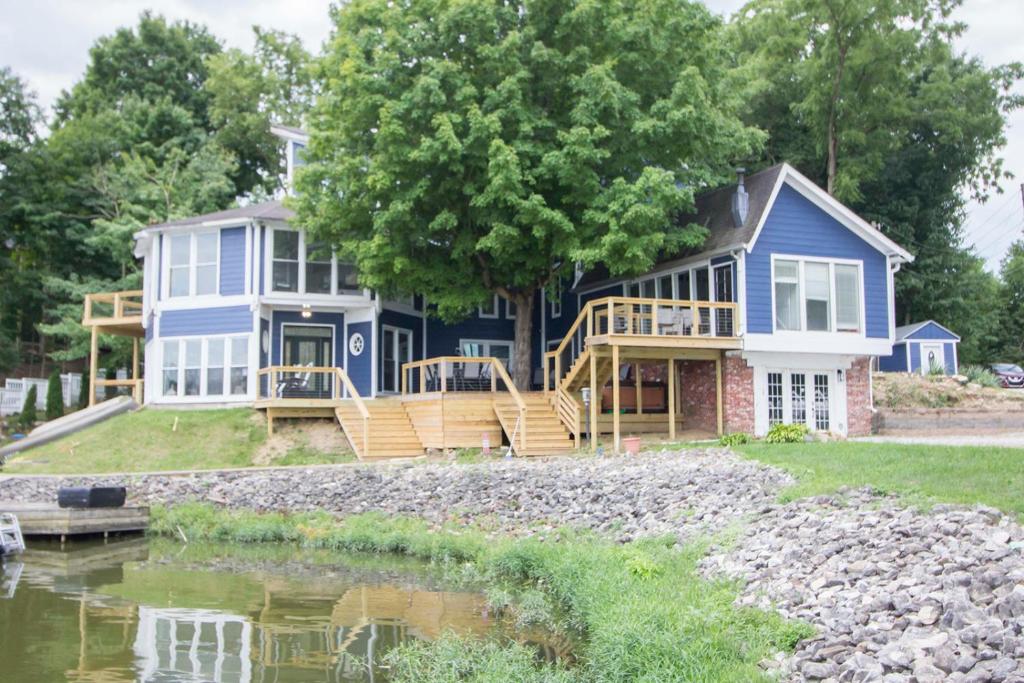 una casa azul con un porche junto a un cuerpo de agua en Little Chi Cottages, en Noblesville