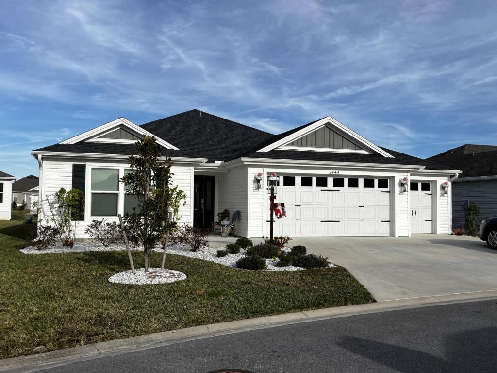 a white house with a garage with a tree in the yard at Relaxing, Golf, Pools, Hiking, events in Wildwood